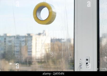 Sigillare le finestre con nastro adesivo durante la guerra in Ucraina per prevenire la formazione di molti frammenti durante l'ondata di esplosione Foto Stock