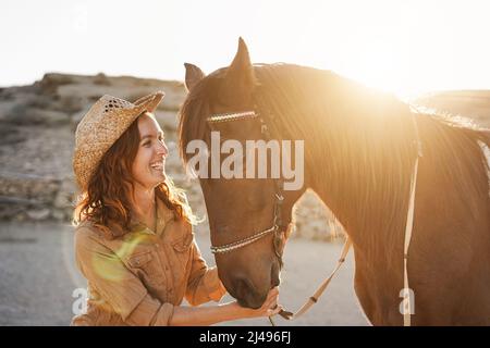 Giovane donna contadina che si diverte con il suo cavallo al ranch fattoria - Focus on Face Foto Stock