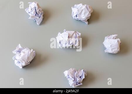 Palle di carta sgualcite su sfondo grigio Foto Stock