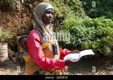 Zainab Nyirazirwanda, 45 anni, vedova il cui marito morì nel 1994. Ha due figli, Shadia Nzayisenga, figlia, 20 e figlio Issa Tuzimana, 17 e nipote, Maniraguha, 2. Prima del programma la sua agricoltura ha prodotto molto poco. Ora dai proventi della sua agricoltura ha comprato una mucca, polli, capre. Ha comprato terra per coltivare mais e vende sale e olio di palma nel mercato. Ha comprato un telefono cellulare e invia suo figlio alla scuola secondaria. Fotografia di Mike Goldwater Foto Stock