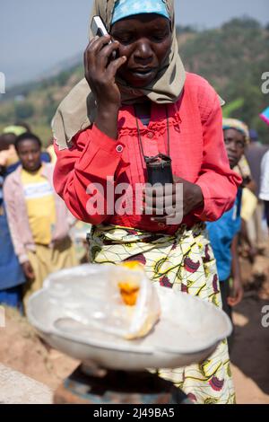 Zainab Nyirazirwanda, 45 anni, vedova il cui marito morì nel 1994. Ha due figli, Shadia Nzayisenga, figlia, 20 e figlio Issa Tuzimana, 17 e nipote, Maniraguha, 2. Prima del programma la sua agricoltura ha prodotto molto poco. Ora dai proventi della sua agricoltura ha comprato una mucca, polli, capre. Ha comprato terra per coltivare mais e vende sale e olio di palma nel mercato. Ha comprato un telefono cellulare e invia suo figlio alla scuola secondaria. Fotografia di Mike Goldwater Foto Stock