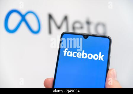 Wroclaw, Polonia - Apr 01, 2022: Facebook cambia il nome della sua azienda in Meta. Facebook su uno smartphone e logo Meta sullo sfondo Foto Stock