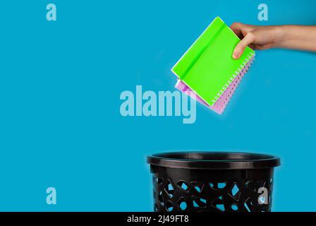 I notebook vengono gettati nel cestino. Per spazio di copia per i designer su sfondo blu Foto Stock