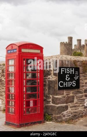 Clichés della Gran Bretagna: Cabina telefonica rossa, mura del castello, segno di fish and chips, cielo stellato. Foto Stock