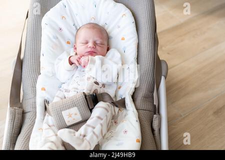 neonato con giorni di vita vestito in piccoli pigiami per essere comodi dorme pacificamente nella sua amaca a dondolo a casa Foto Stock