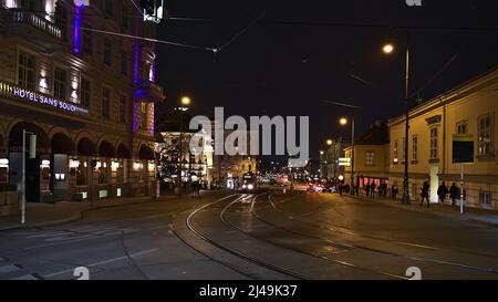 Vista notturna della strada illuminata Burggasse nel centro storico di Vienna, Austria, con l'avvicinarsi del tram, hotel e Volkstheater. Foto Stock
