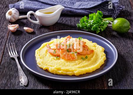 Polenta e schie fritte, piatto veneziano, polenta con gamberetti fritti su un piatto su tavola di legno scuro con aglio una salsa sullo sfondo, vista orizzontale fr Foto Stock