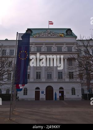 Vista frontale dell'edificio principale dell'università tu Wien nel centro storico di Vienna, Austria, in una giornata nuvolosa in primavera con logo e bandiere. Foto Stock