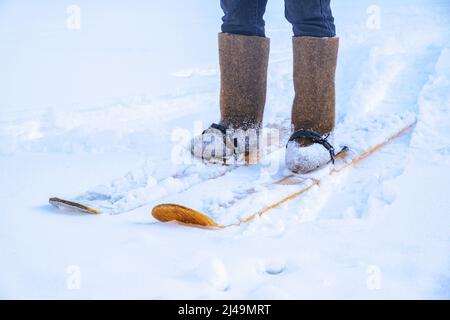 Un uomo in felt stivali su sci fatti in casa cammina attraverso la neve nella foresta. Escursioni, viaggi, caccia, pesca. Foto Stock