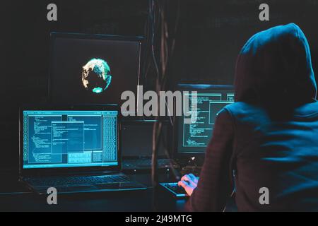 Hacker con attacco posteriore che utilizza software dannoso hack data center aziendale. Malefactor nascosto sottoterra in un luogo buio, più display con phishing Foto Stock