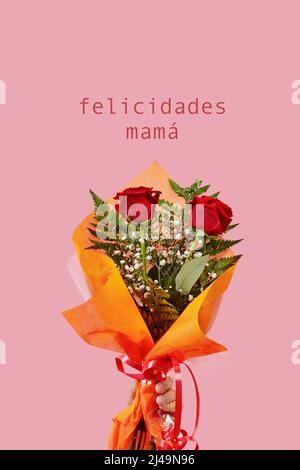 primo piano di un uomo con un bouquet di fiori in mano e il testo congratulazioni mamma, scritto in spagnolo, su uno sfondo rosa Foto Stock