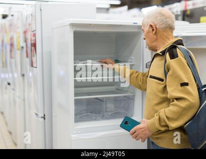 senor uomo pensionato acquistare frigorifero in showroom di elettrodomestici negozio Foto Stock