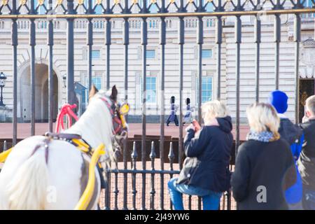 I cavalli sono legati alle ringhiere mentre le persone si riuniscono fuori da Buckingham Palace nel centro di Londra prima dell'adesione Day. Foto Stock