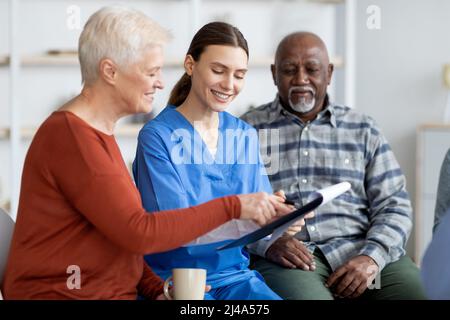 Ragazza allegra medico che ha conversato con i pazienti anziani Foto Stock