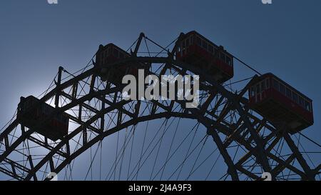 Silhouette della cima di una famosa ruota panoramica (Riesenrad) nel parco divertimenti Wurstelprater a Vienna, Austria, in una giornata di sole con retroilluminazione. Foto Stock