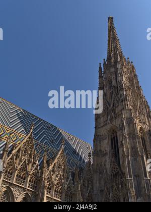 Bella vista ad angolo basso della torre della chiesa Cattedrale di Santo Stefano (in tedesco: Stephansdom) nel centro storico di Vienna, Austria in giornata di sole. Foto Stock