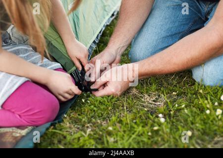 Posso aiutarmi, papà. Scatto corto di una bambina che aiuta suo padre a mettere su una tenda. Foto Stock