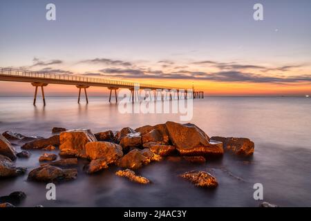 Il molo marino di Badalona in Spagna con alcune rocce prima dell'alba Foto Stock