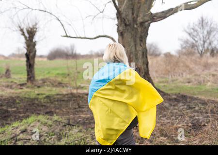 bandiera della donna dell'ucraina vicino all'albero bruciato Foto Stock