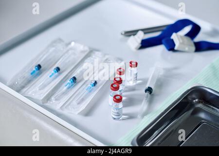 Primo piano delle siringhe e dei flaconi confezionati con il medicinale sul tavolo preparazione per la vaccinazione dal virus Foto Stock