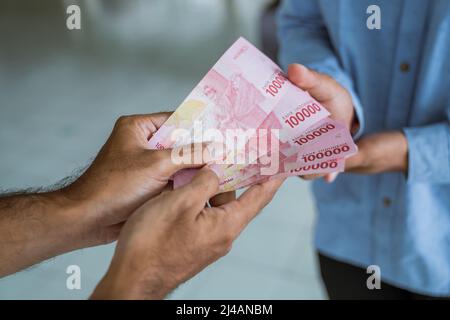 musulmano che paga un po 'di zakat carità utilizzando denaro presso la moschea Foto Stock