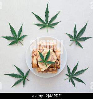 Rotolo dolce con olio di marijuana su piatto bianco. Cucina di cannabis. Disposizione dei deliziosi dessert, vista dall'alto da vicino. Foto Stock