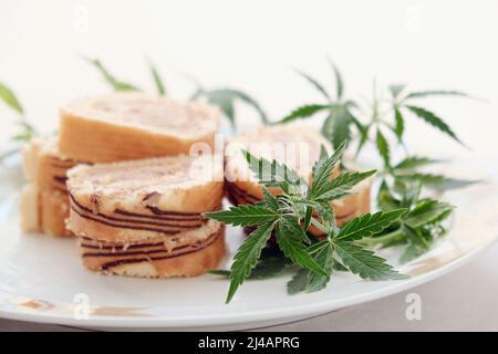 Rotolo dolce con olio di marijuana su piatto bianco. Cucina di cannabis. Delizioso primo piano con dessert. Foto Stock