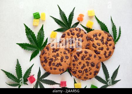 Biscotti americani con estratto di cannabis. Dolci con olio CBD. Foglie di marijuana su sfondo bianco. Vista dall'alto, piatto. Foto Stock