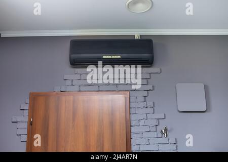 moderno condizionatore d'aria nero appeso a pareti di mattoni bianchi. Foto di alta qualità. Foto Stock