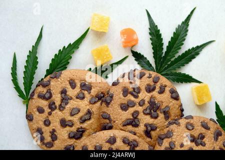 Biscotti americani con estratto di cannabis. Dolci con olio CBD. Foglie di marijuana su sfondo bianco. Vista dall'alto, piatto. Foto Stock