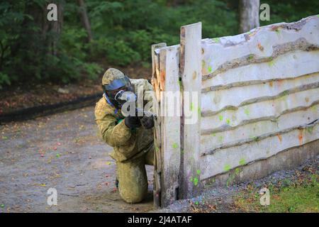 Il giocatore di paintball in full gear spara al poligono di tiro Foto Stock