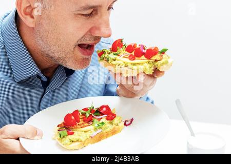 Sano panino vegano aperto con purè di avocado, zucchine, pomodori ciliegini, formaggio sul pane di mais. Cibo sano, concetto di cibo vegetariano Foto Stock