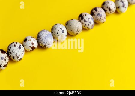 piccole uova di quaglia macchiate sparse su tessuto beige e bouquet di fiori di gypsofila blu secchi. Foto Stock