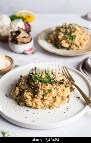 Risotto ai funghi porcini su un piatto piccolo e condito con aneto fresco Foto Stock