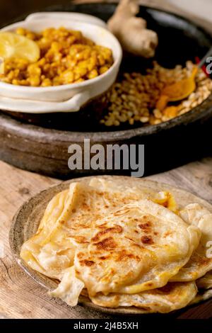 Dhal fatto in casa con pane di roti. Tradizionale piselli indiani gialli dal con pan piatto di roti, servito con limone in ciotola di ceramica su vecchio tavolo di legno. Foto Stock