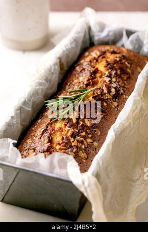 Torta al limone fatta in casa con noci e rosmarino in forno su tavola di marmo bianco. Primo piano Foto Stock