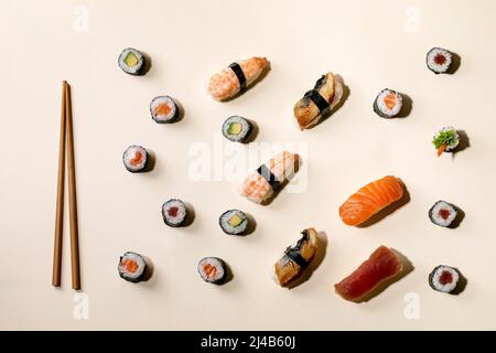 Set di sushi roll. Sushi tradizionale giapponese e panini con salmone fresco, tonno, anguilla e gamberi su riso, chopsics di legno su sfondo beige con Foto Stock