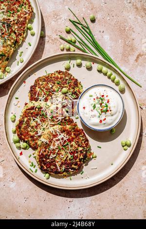 zucchine, piselli, erba cipollina, parmigiano grattugiato, pentola di crema piccante, in piatto bianco Foto Stock