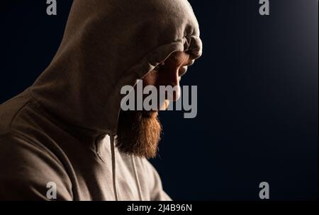 uomo con cappuccio su sfondo scuro depressione o hacker Foto Stock