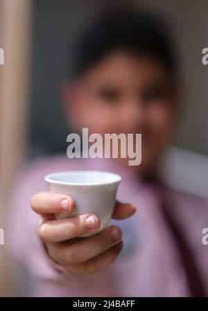 bokeh foto di ragazzo porta una tazza di caffè arabico Foto Stock