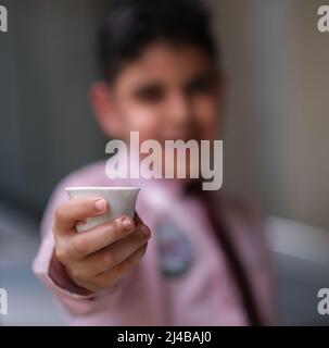 bokeh foto di ragazzo porta una tazza di caffè arabico Foto Stock