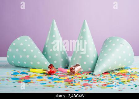 Berretti di compleanno, soffiatori e confetti sullo sfondo Foto Stock