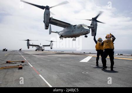 220204-N-VS068-2049 OCEANO PACIFICO (11 aprile 2022) – Aviation Boatswain’s Mate (Handling) Airman Darien Haq, a sinistra, E Aviation Boatswain’s Mate (Handling) 2nd Class Colin Fidel dirigono una MV-22 Osprey, assegnata alla Marine Medium Tiltrotor Squadron (VMM) 362, sul ponte di volo della nave d’assalto anfibio USS Makin Island (LHD 8), aprile 11. I piloti eseguono le qualifiche di atterraggio sul ponte per praticare i decolli e gli sbarchi a bordo delle navi. Makin Island sta conducendo operazioni di routine nella flotta USA 3rd. (STATI UNITI Foto della Marina di Seaman Kendra Helmbrecht, specialista della comunicazione di massa) Foto Stock