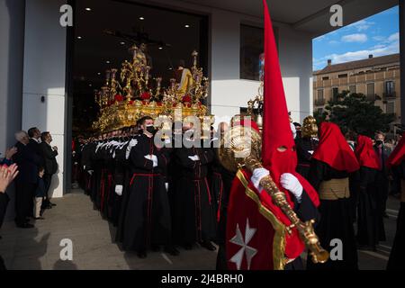 Malaga, Spagna. 13th Apr 2022. I Penitenti della fraternità 'Fusionadas' sono visti portare un galleggiante ornato con la statua di Cristo durante il Mercoledì Santo, per celebrare le celebrazioni della settimana Santa. Dopo due anni senza la settimana Santa a causa della pandemia del coronavirus, migliaia di fedeli attendono di vedere le processioni che portano le statue di Cristo e della Vergine Maria per le strade come parte della settimana Santa tradizionale. Credit: SOPA Images Limited/Alamy Live News Foto Stock