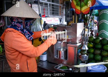 Ho Chi Minh City, Vietnam, 13 aprile 2022: Donna che spreme il succo di canna da zucchero. Popolare Street drink a ho Chi Minh City, Vietnam Foto Stock