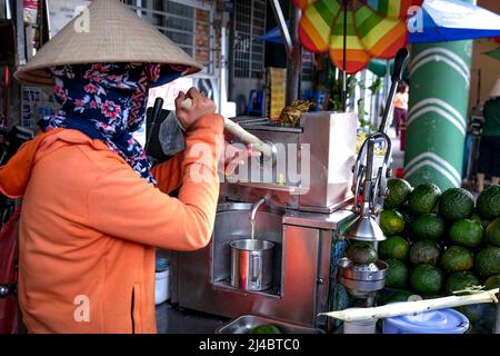 Ho Chi Minh City, Vietnam, 13 aprile 2022: Donna che spreme il succo di canna da zucchero. Popolare Street drink a ho Chi Minh City, Vietnam Foto Stock