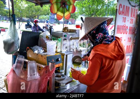 Ho Chi Minh City, Vietnam, 13 aprile 2022: Donna che spreme il succo di canna da zucchero. Popolare Street drink a ho Chi Minh City, Vietnam Foto Stock