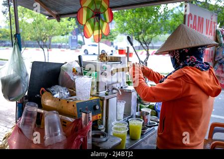 Ho Chi Minh City, Vietnam, 13 aprile 2022: Donna che spreme il succo di canna da zucchero. Popolare Street drink a ho Chi Minh City, Vietnam Foto Stock