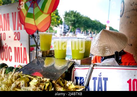 Ho Chi Minh City, Vietnam, 13 aprile 2022: Donna che spreme il succo di canna da zucchero. Popolare Street drink a ho Chi Minh City, Vietnam Foto Stock