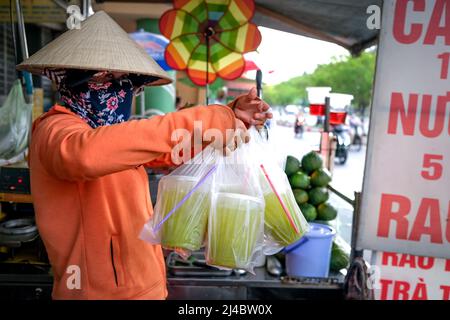 Ho Chi Minh City, Vietnam, 13 aprile 2022: Donna che spreme il succo di canna da zucchero. Popolare Street drink a ho Chi Minh City, Vietnam Foto Stock